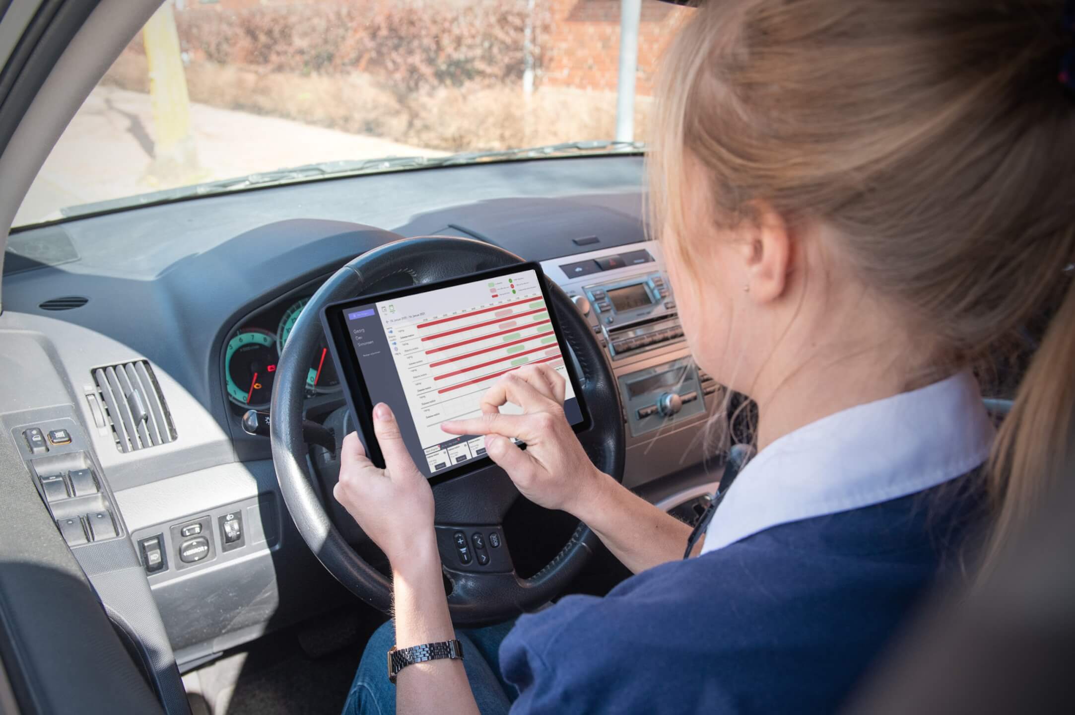 Care professional sitting in her car with her tablet, showing the Klikkit dashboard.